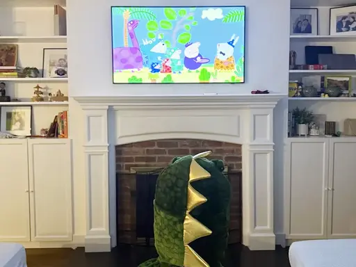 Lucca in a dinosaur costume watching Peppa Pig at home